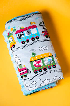 Sweet and cozy baby blanket with train pattern isolated on yellow backgroundの写真素材