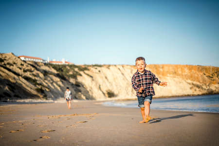The small boy happily running on the beach by sunset, Algarve, Portugalの写真素材