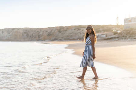Portrait of a beautiful young woman on the beach by sunset in Algarve, Portugalの写真素材