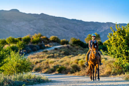Young woman enjoying horse riding in the mountainous wilderness of Andalusia, Spainの写真素材