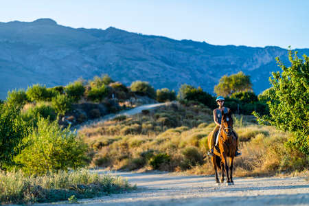 Young woman enjoying horse riding in the mountainous wilderness of Andalusia, Spainの写真素材