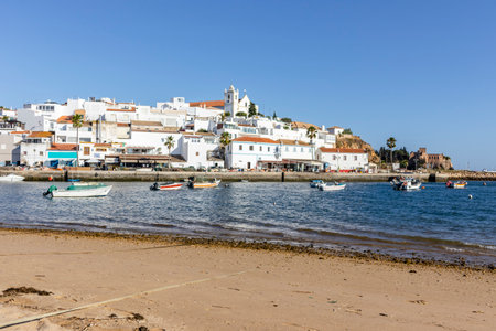 Cityscape of Ferragudo with whitewashed architecture and boats in the foreground, Algarve, Portugalの写真素材