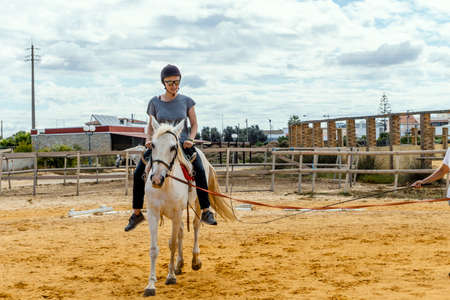 Portrait of a woman taking horse riding lessons in a paddockの写真素材