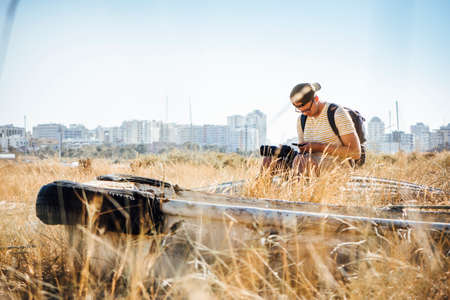 Tourist with a camera and phone sitting among dry grass, Portugalの写真素材