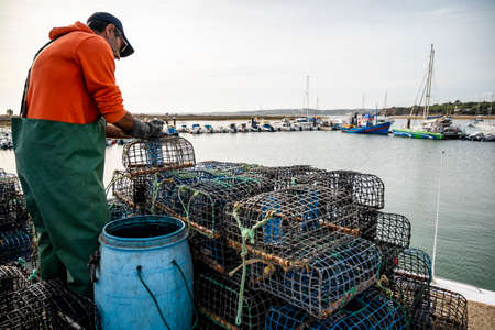 Alvor, Portugal - October 28, 2021: Fisherman puts crab inside octopus traps at the local harborのeditorial素材
