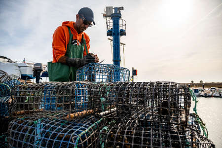 Alvor, Portugal - October 28, 2021: Fisherman puts crab inside octopus traps at the local harbor