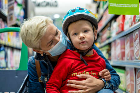 Porto, Portugal - September 25, 2021: Mother in mask shopping with her 3 years old son in the supermarketのeditorial素材