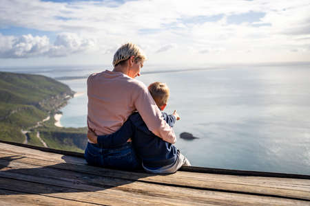 Mother and 3 years old son hugging each other and enjoying the beautiful ocean views, Portugalの写真素材