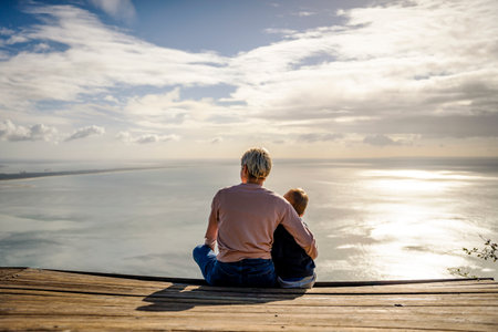 Mother and 3 years old son hugging each other and enjoying the beautiful ocean views, Portugalの写真素材