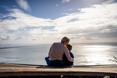 Mother and 3 years old son hugging each other and enjoying the beautiful ocean views, Portugalの写真素材