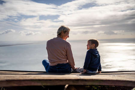 Mother and 3 years old son talking to each other having the beautiful ocean view, Portugalの写真素材