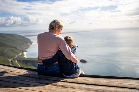 Mother and 3 years old son hugging each other and enjoying the beautiful ocean views, Portugalの写真素材