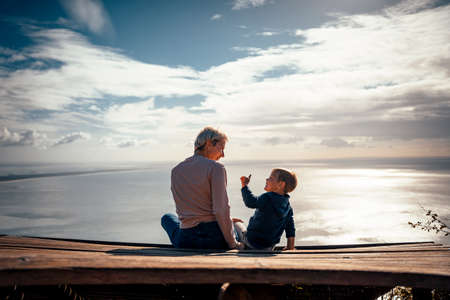 Mother and 3 years old son talking to each other having the beautiful ocean view, Portugalの写真素材