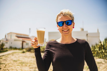 Happy woman with big coffee with milk during vacations in Portugalの写真素材