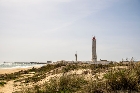 Beach, dunes and lighthouse at Farol Island, Faro District, Algarve, Portugalの写真素材