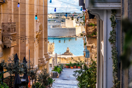 Charming downhill street illuminated with colorful bulbs in Valletta, Malta. St Angelo Fortress in the background.の写真素材