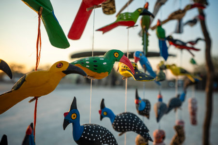 Colorful hand-painted wooden bird ornaments hanging on strings at a roadside craft stall in Namibia, showcasing bright African folk art, Himba, Etoshaの写真素材
