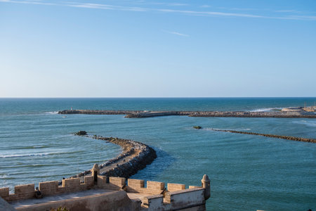 Rabat, Morocco â Scenic view of the historic Kasbah of the Udayas overlooking the Atlantic Ocean. The Moroccan flag waves above the ancient fortress walls near the sea, with stone pathways and blue water under a clear sky. A peaceful and picturesque scene showcasing Moroccan heritage and coastal beauty.の写真素材