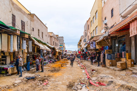 Casablanca, Morocco â April 19, 2025: Street scene in the old medina showing people walking and shopping along a lively alley with traditional architecture and arched doorways. The image captures the vibrant daily life and cultural atmosphere of this historic North African city, blending tradition and modern urban energyの写真素材