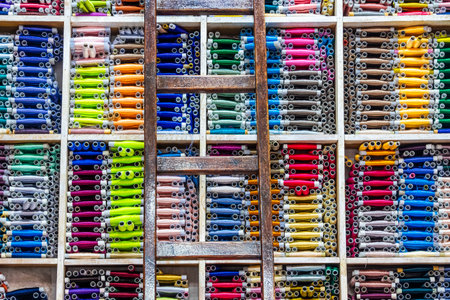 Fes, Morocco â Vibrant display of colorful fabric rolls neatly stacked in a traditional Moroccan textile shop. The organized shelves and wooden ladder create a visually striking pattern of bright colors and textures. A perfect representation of Moroccan craftsmanship, culture, and artisanal trade in one of the country's oldest medinas.の写真素材