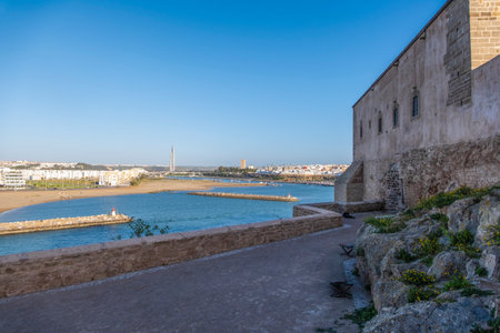 Rabat, Morocco â Scenic view of the historic Kasbah of the Udayas overlooking the Atlantic Ocean. The Moroccan flag waves above the ancient fortress walls near the sea, with stone pathways and blue water under a clear sky. A peaceful and picturesque scene showcasing Moroccan heritage and coastal beauty.の写真素材