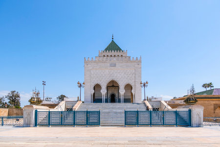 Rabat, Morocco â The Mausoleum of Mohammed V, an architectural masterpiece of Moroccan craftsmanship, stands elegantly under a clear blue sky. The white marble structure features intricate arches, detailed geometric patterns, and traditional Islamic design elements.の写真素材