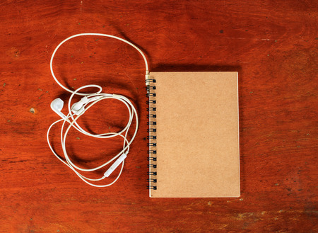 book brown with white headphone on wood tableの写真素材