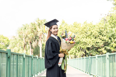 happy graduate  flower bouquet in hand with in the gardenの写真素材