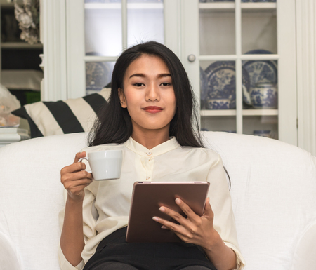 business women holding teblet in livingroomの写真素材