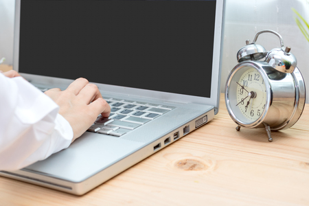 women working job on laptop in morning with old clock on tableの写真素材