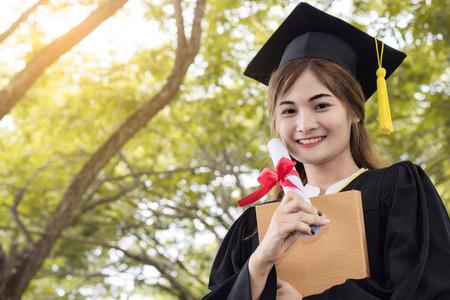 student graduate holding certificated in hand with in the gardenの写真素材