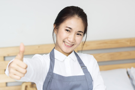 Asian women maid happy working in bedroom in homeの写真素材