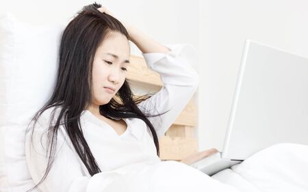 beautiful Asian women working in laptop with in the morning on bedの写真素材