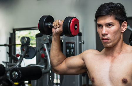 Man exercise in gym with dumbbellの写真素材