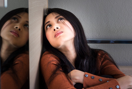 Sad girl sitting on the floor in corner of room.Unhappy depressed teenager