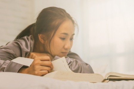 women read book to learning on bed in bed room in the morning.の写真素材