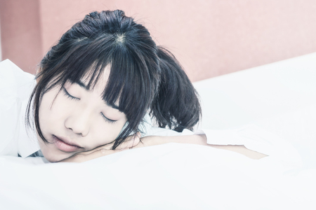 Asian woman wake up on bed in bedroom in the morning.at home in holiday.の写真素材
