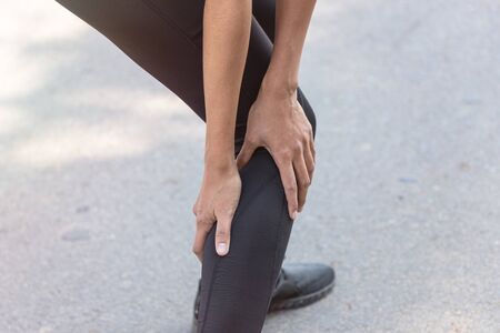 Close up Athlete running woman use hands hold on his ankle while running in the morning.Ankle injury on woman after traning for warm up her muscle.の写真素材