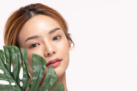 Beauty asian woman holds a large green tropical leaf in hands.の写真素材