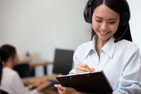 Asian business woman take note and talk job in businessの写真素材