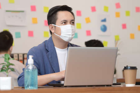 Business man working job on labtop and wering mask in office.