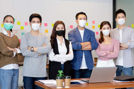 Business asian man stand and wear masks and cross arm in the office.の写真素材