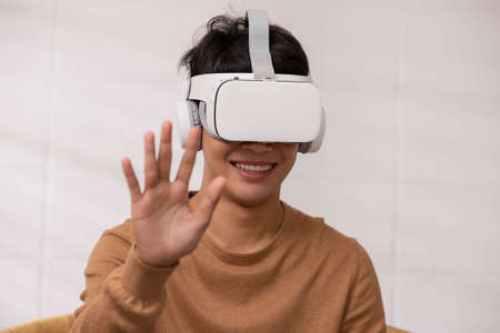 Asian man wearing virtual reality goggles in modern coworking studio. Smartphone using with VR...