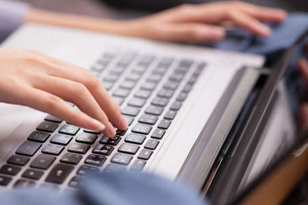 Enjoying the moment. At work, an Asian designer sits on a desk with his laptop, tablet, and...