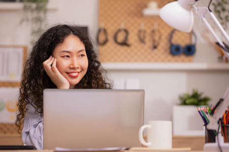 In the morning,Asian working woman relaxes on the sofa with her laptop, working from home.の写真素材