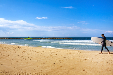 surfer with a board goes along the seaの写真素材