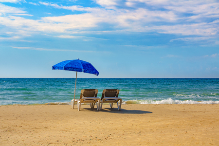 Two sunbeds under an umbrella on the beachの写真素材