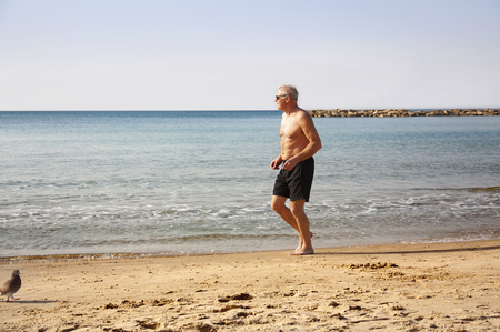A man over 60 years engaged in gymnastics on the beachの写真素材