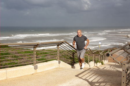 Mature man jogging in the bad weatherの写真素材