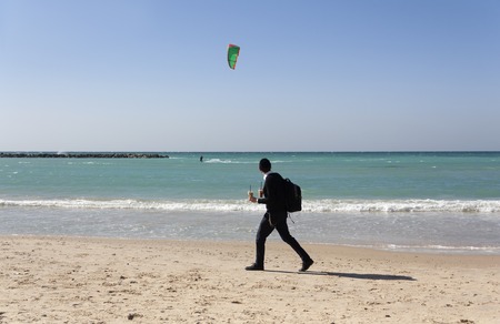 the student walks along the sea with two paper cup of cocktail in his hands and looks at the sea at...